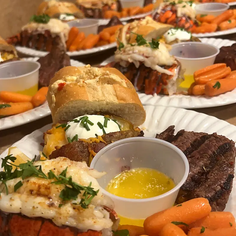 Plated steak and lobster dinners lined up for service
