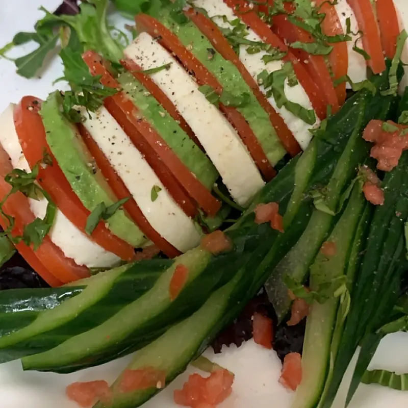 Caprese salad plated with tomato, mozzarella and green beans