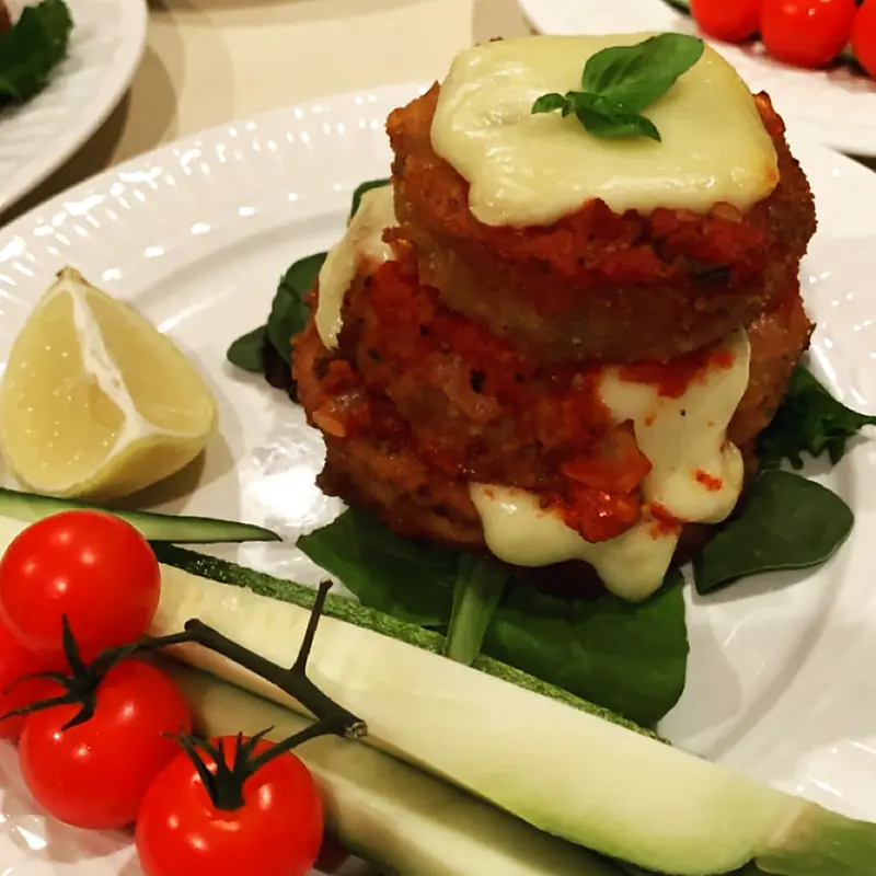 Stacked eggplant parmesan with melted mozzarella and vine tomatoes